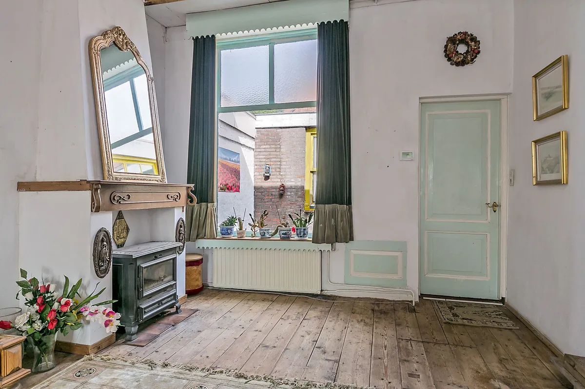 Karakteristieke woonkamer in Hellevoetsluis met schouw, spiegel, brede planken vloer en hoog raam