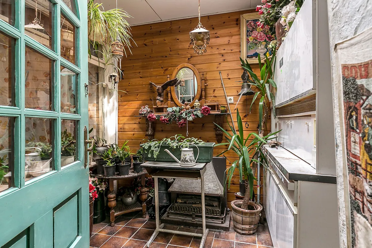 Serre met groene glazen deuren, bakstenen muur en planten in een woning in Hellevoetsluis