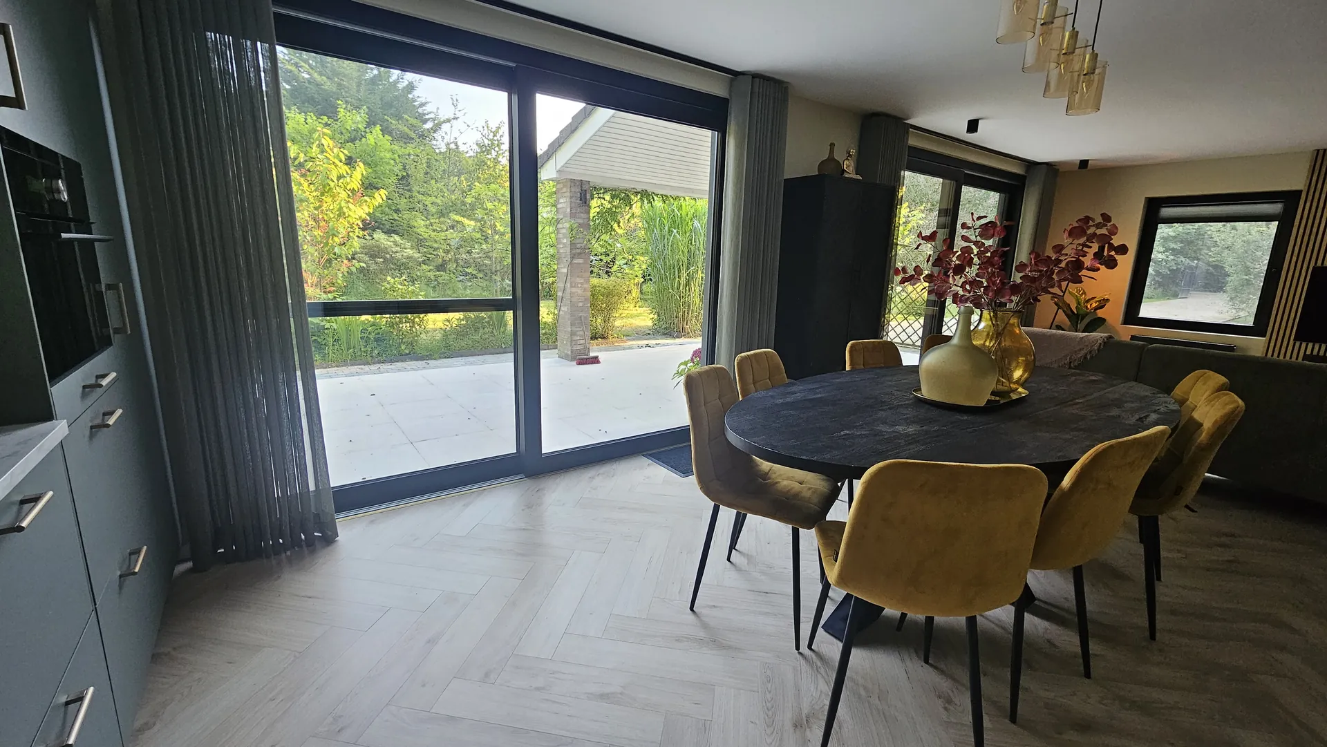 Eetkamer met grote schuifpui naar het terras na de uitbreiding van een woning