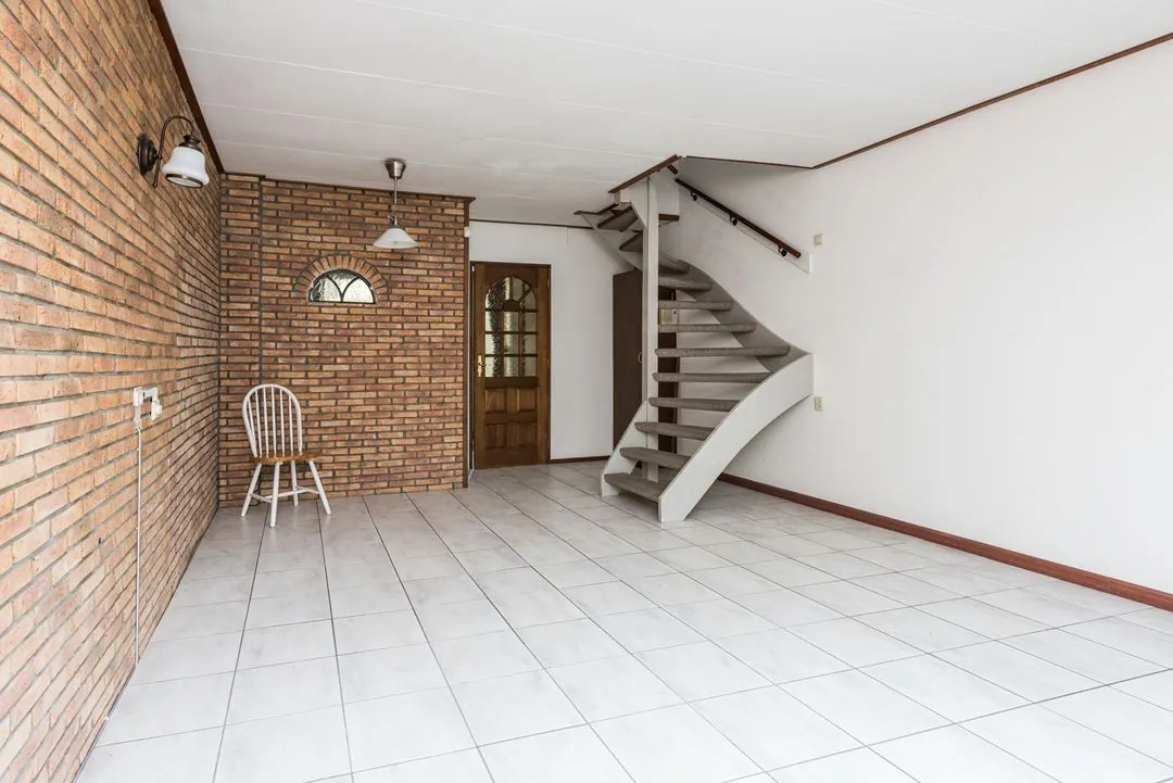 Gerenoveerde bakstenen wand en open trap in een Rotterdams appartement