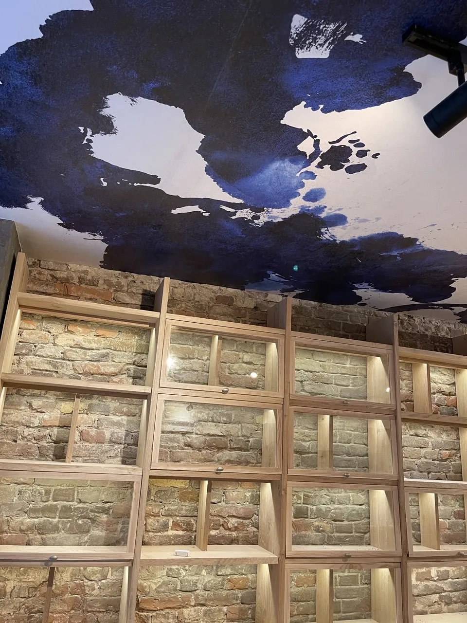Aziatisch restaurant in Amsterdam met beschilderd wolkenplafond boven verlichte houten wandkasten