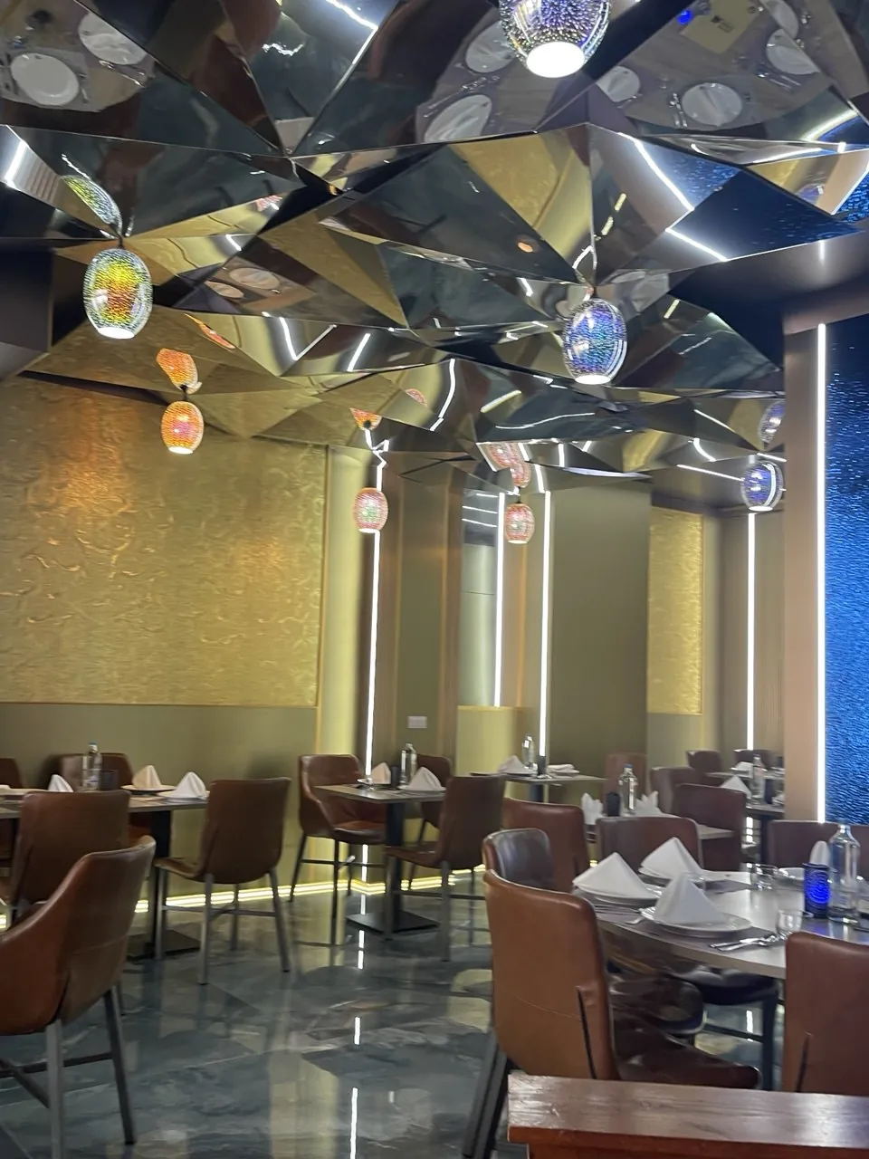Eetzaal van een Indiaas restaurant in Rotterdam met gefacetteerd spiegelplafond en gouden wanden